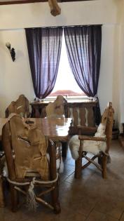 Rustikaler Tisch mit 10 Stühle die mit Lammfell belegt sind